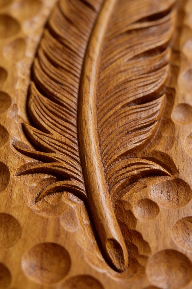 Feather wood carving detail showing individual barb lines and central quill