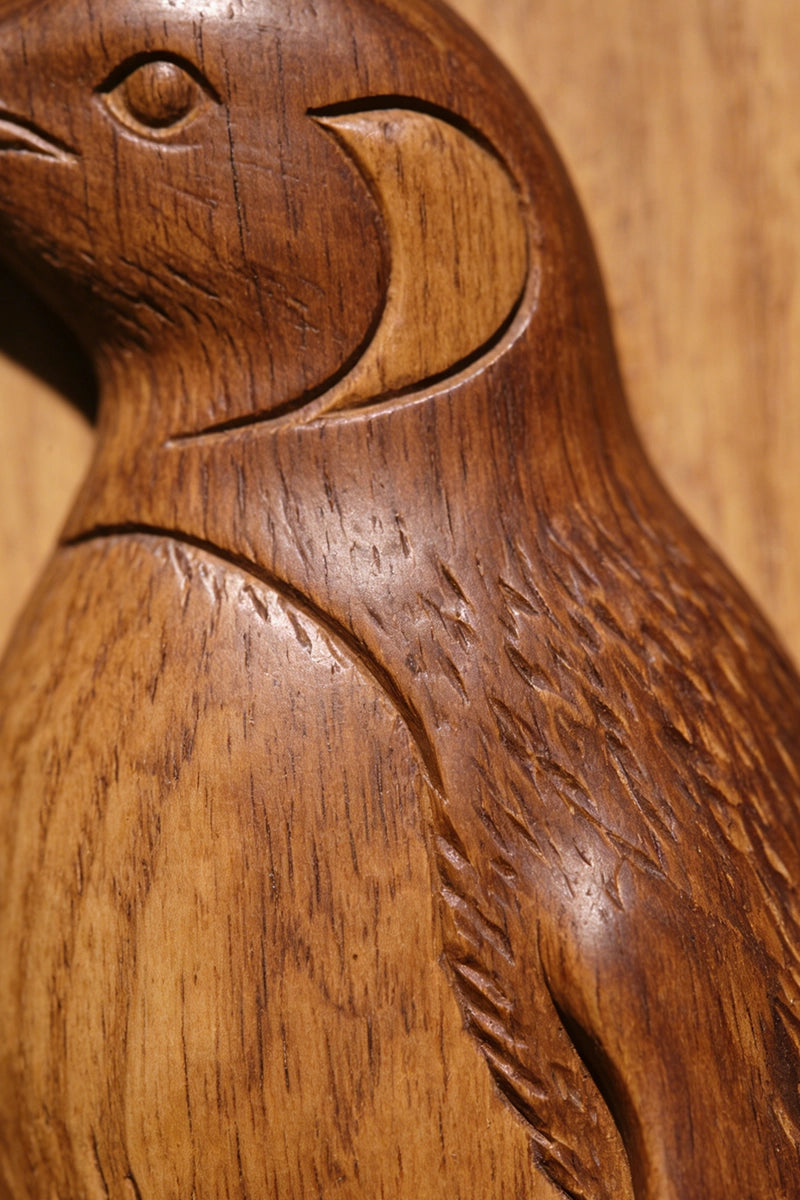 Penguin wood carving detail showing feather layers and rocky coastline texture
