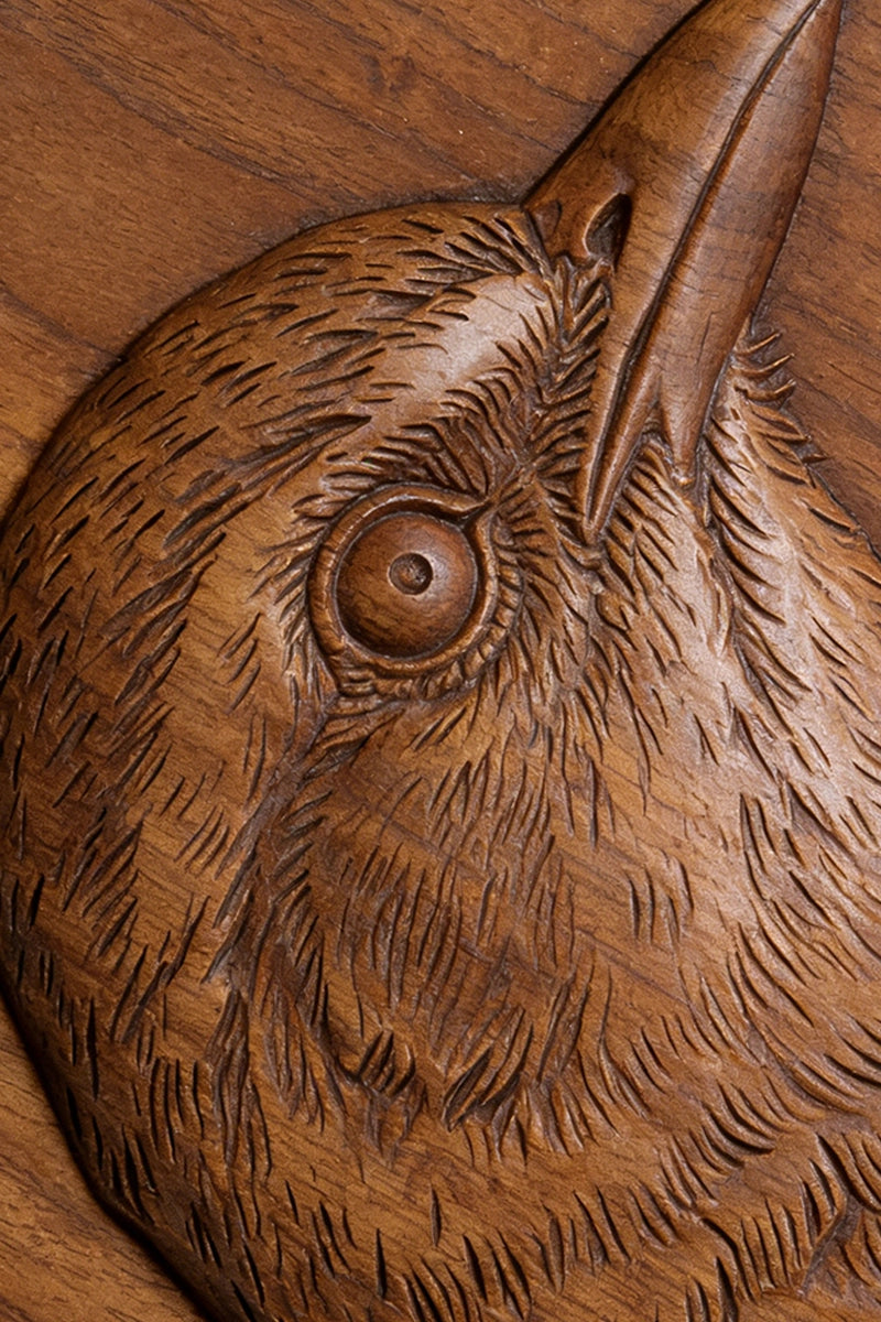Crow wood carving detail showing eye, beak, and layered plumage